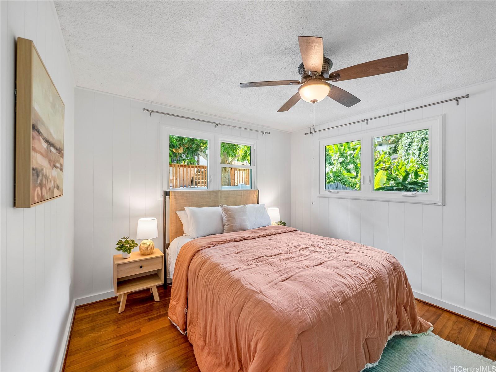 Guest bedroom with hardwood floors and dual windows